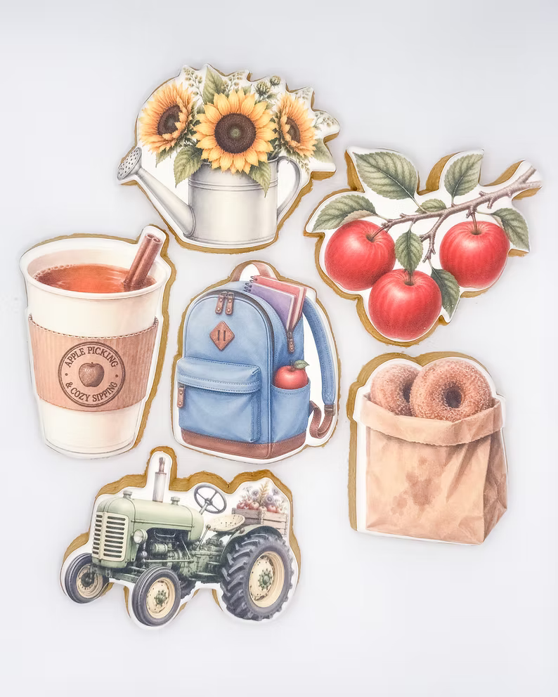 A set of six die-cut sticker designs featuring autumn and farm-themed illustrations, including sunflowers in a watering can, red apples on a branch, an apple cider cup, a blue backpack, a green tractor, and a paper bag of donuts, arranged on a light gray background.