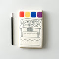 A rectangular white product, likely a small plaque, coaster, or decorative tile, featuring a black line art drawing of a birthday cake and banner that reads 'HAPPY B-DAY'. Above the illustration are four colored squares in red, yellow, blue, and purple.